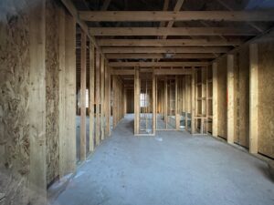 Framed interior of a building under construction with exposed wooden beams and unfinished walls.