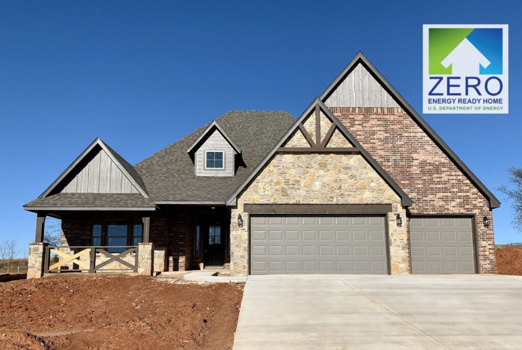 A modern brick and stone house with a double garage and a Zero Energy Ready Home logo in the corner.