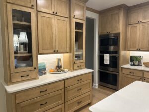 Wooden kitchen cabinets and drawers with modern appliances, including an oven and microwave. White countertops, decorative items, and under-cabinet lighting are present.