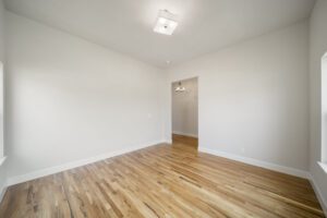Empty room with white walls, recessed lighting, and hardwood floor.