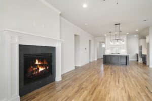 Modern home interior featuring a lit fireplace, hardwood floors, and an open layout with a view of a white kitchen island.