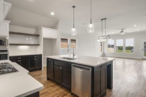 Modern kitchen with white walls, dark cabinetry, an island with a sink, and pendant lighting.