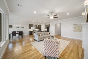 Spacious living room with hardwood floors, connected to an open kitchen, featuring modern furnishings and neutral colors.