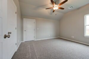 Empty room with gray carpet, white walls, a ceiling fan, and two closed doors.