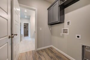 A modern hallway with light gray walls, wooden flooring, a black cabinet, and a small picture frame on the wall.