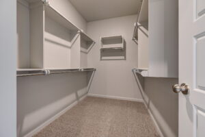 Empty walk-in closet with carpeted floor and built-in shelving.