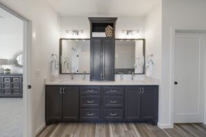 Modern bathroom interior with a double vanity in dark blue, white countertops, twin sinks, large mirror, and cabinet storage.