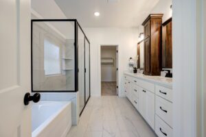 A modern bathroom with a glass shower, white bathtub, dual-sink vanity with dark wood cabinets, and marble tile flooring.